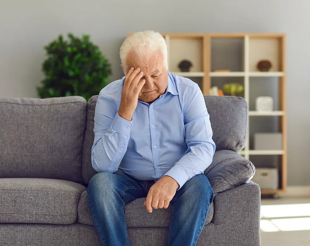 Older man sitting on a couch in grief